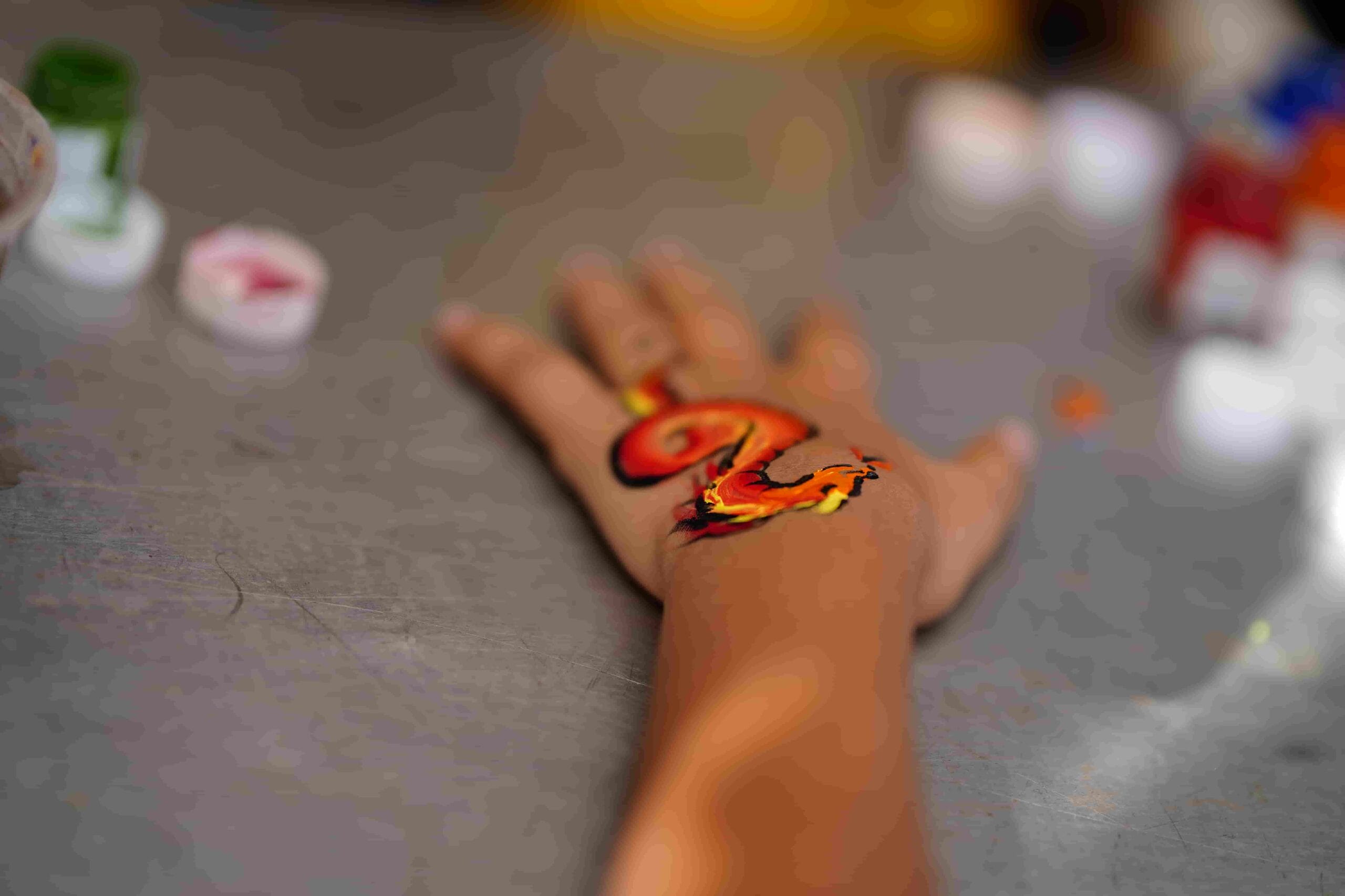 A boy gets his hand painted with a dragon picture.