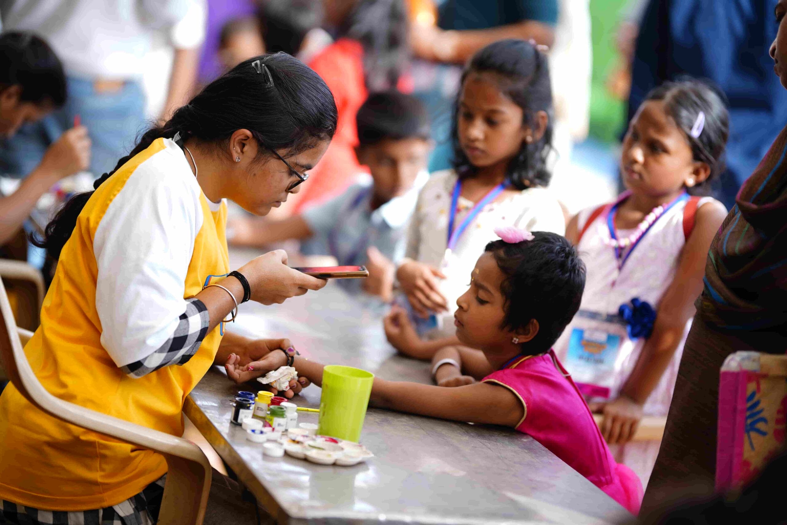 A volunteer captures a snapshot of the artwork they painted on a child's hand.