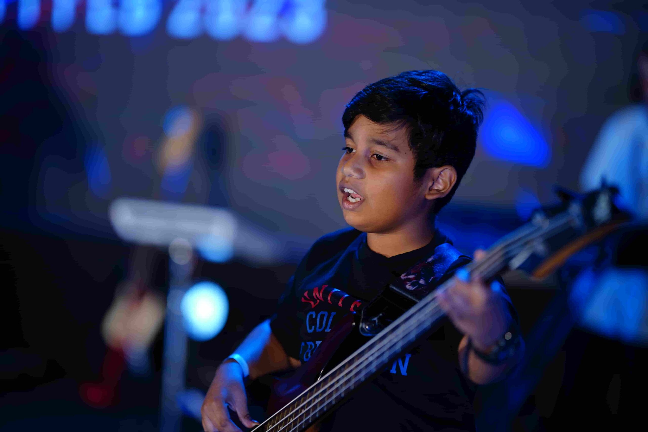 Image of a boy singing on stage with a guitar at the fest.