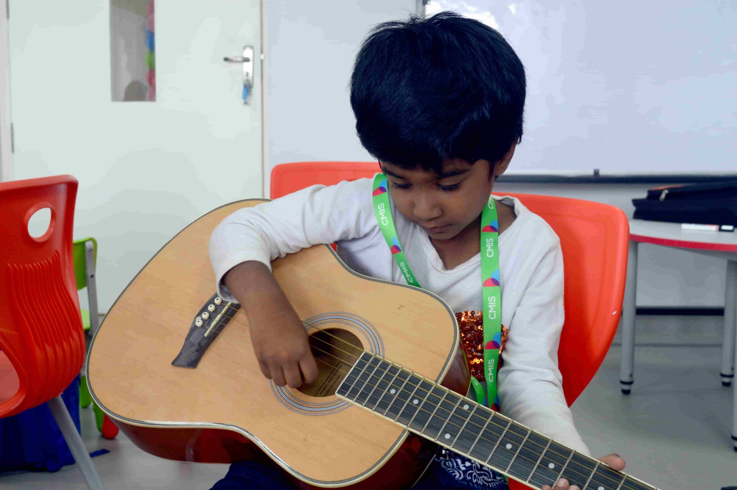 A small girl playing guitar at CMIS.