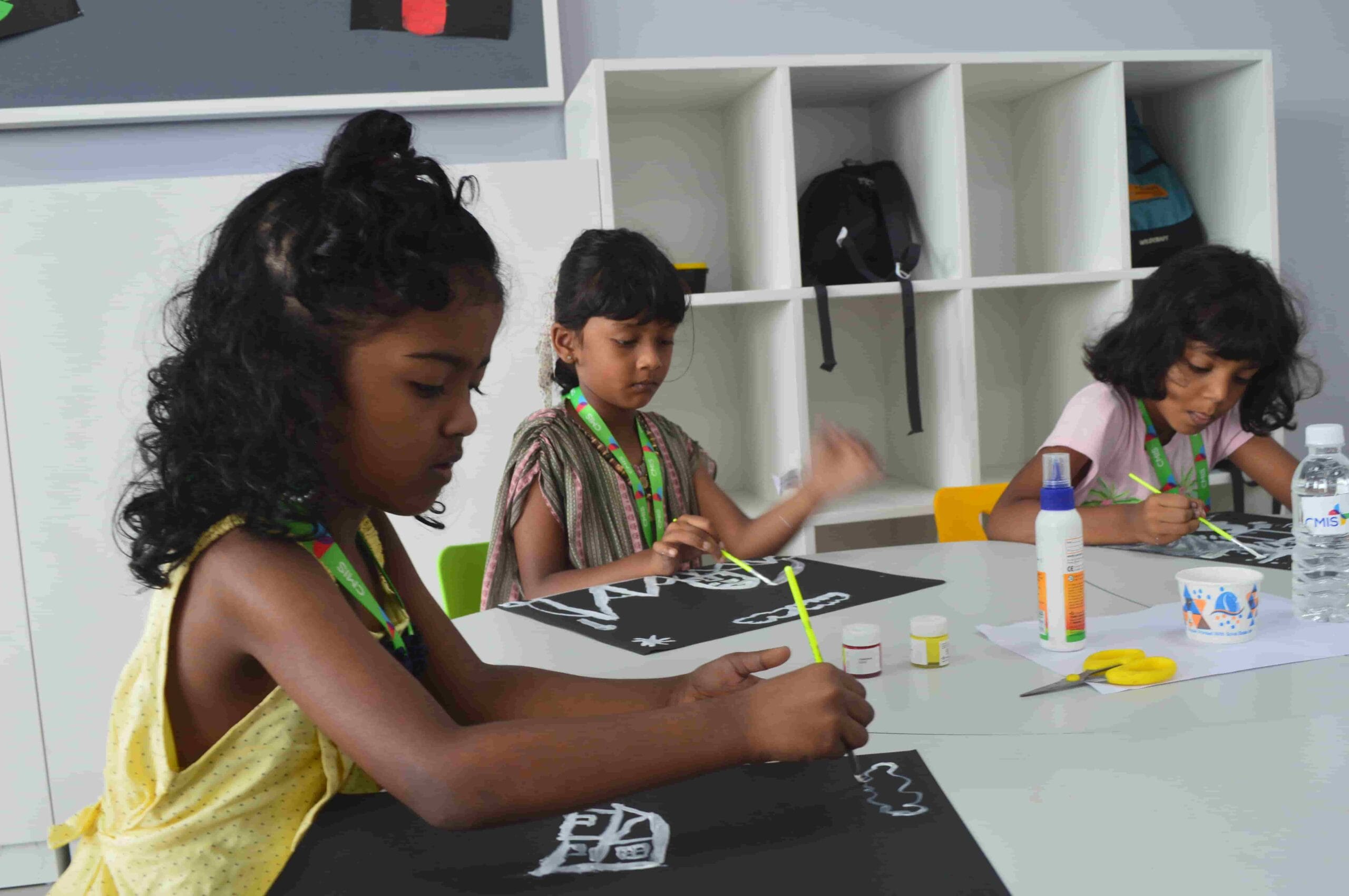 Students paint on black charts.