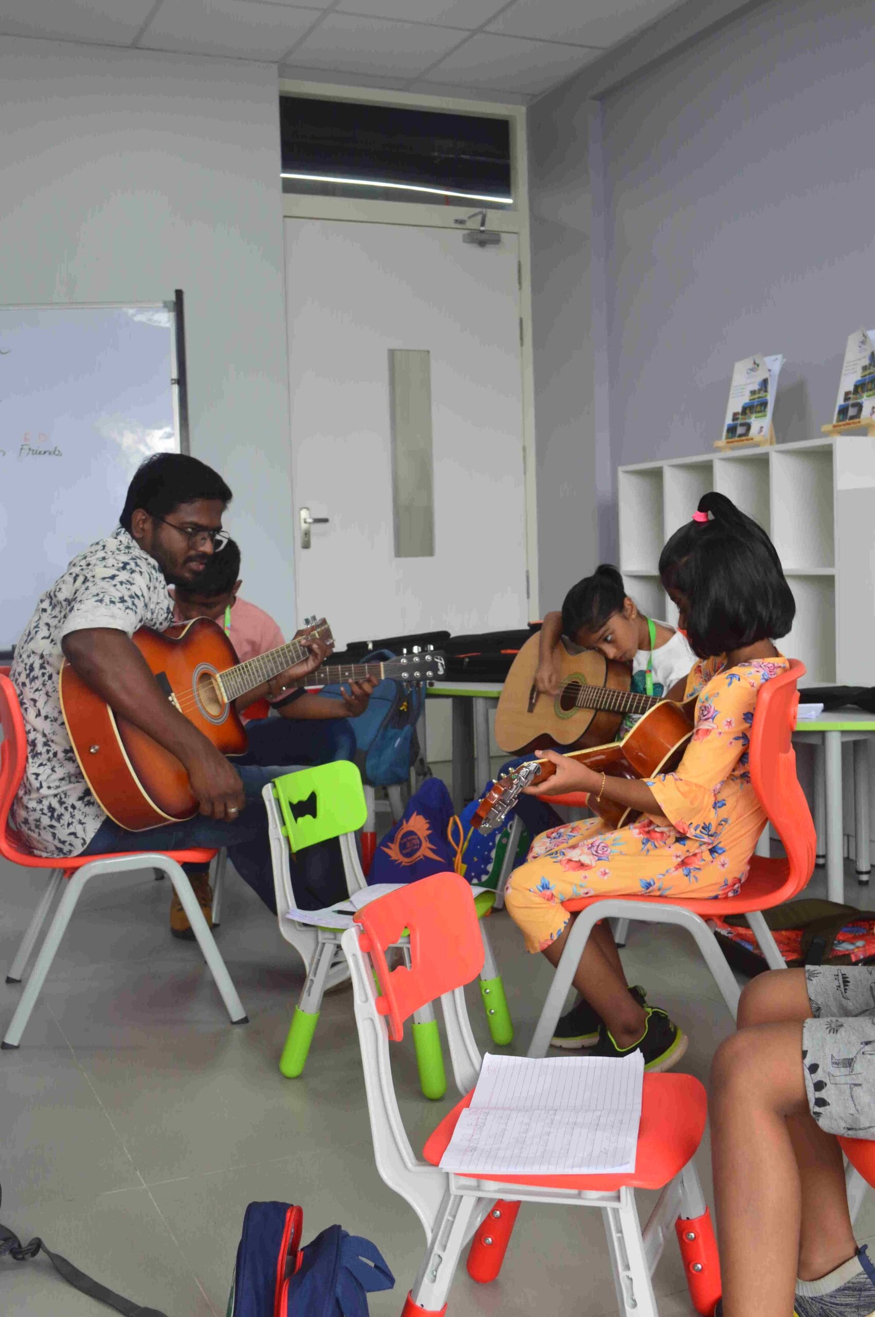 A music teacher teaches guitar to his students.