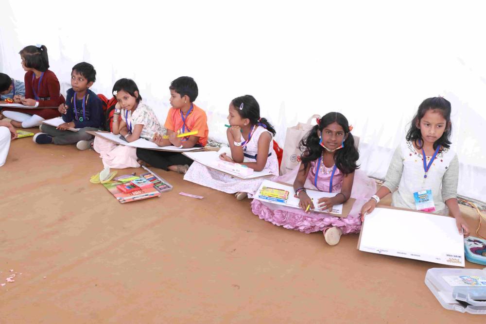 A group of children with drawing sheets and colouring materials in an event at the fest.