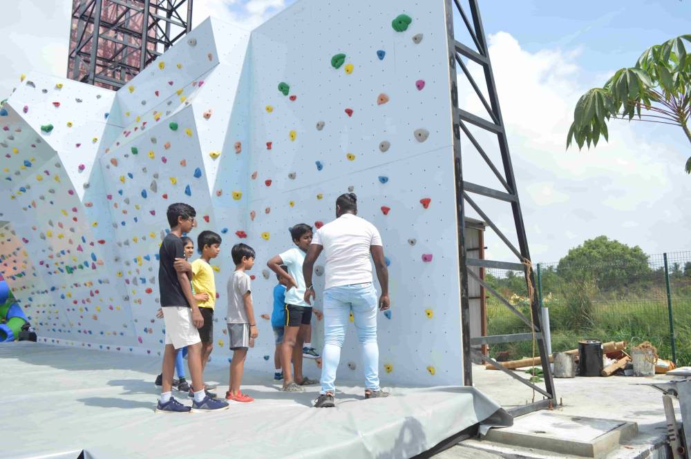 A volunteer gives instructions to students before climbing the wall.
