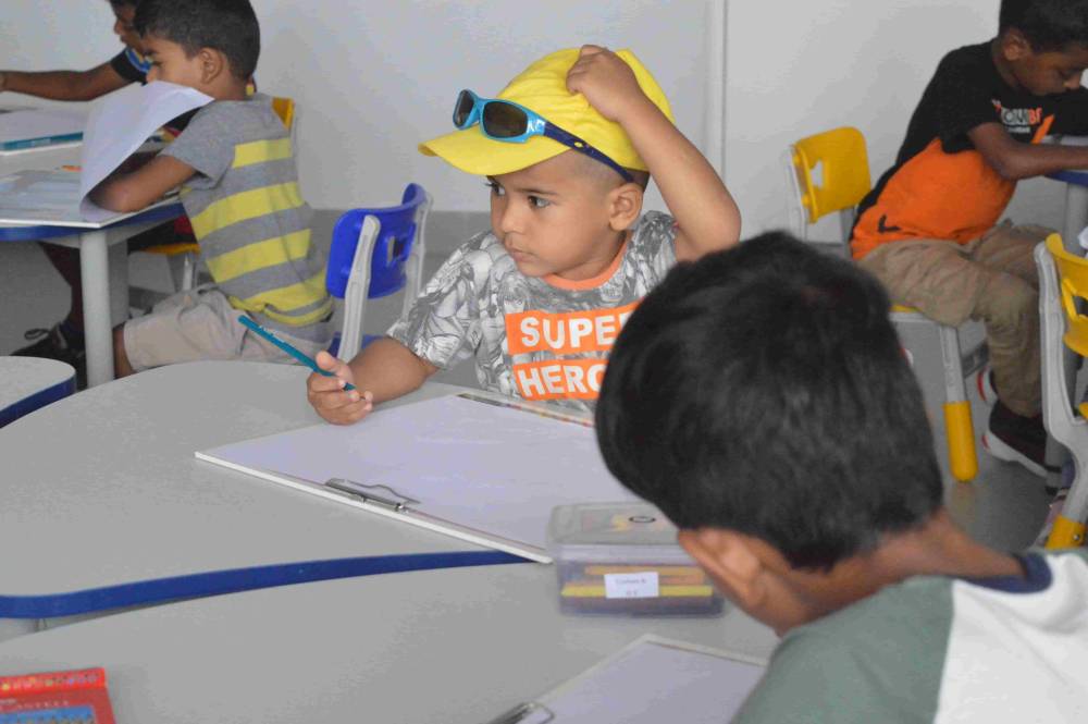 A stylish boy with a cap and sunglasses inside a classroom at CMIS.