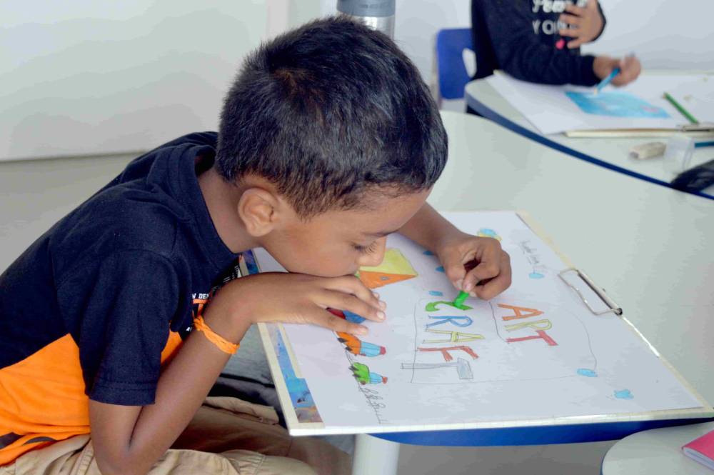 The small boy colouring his drawing at CMIS.