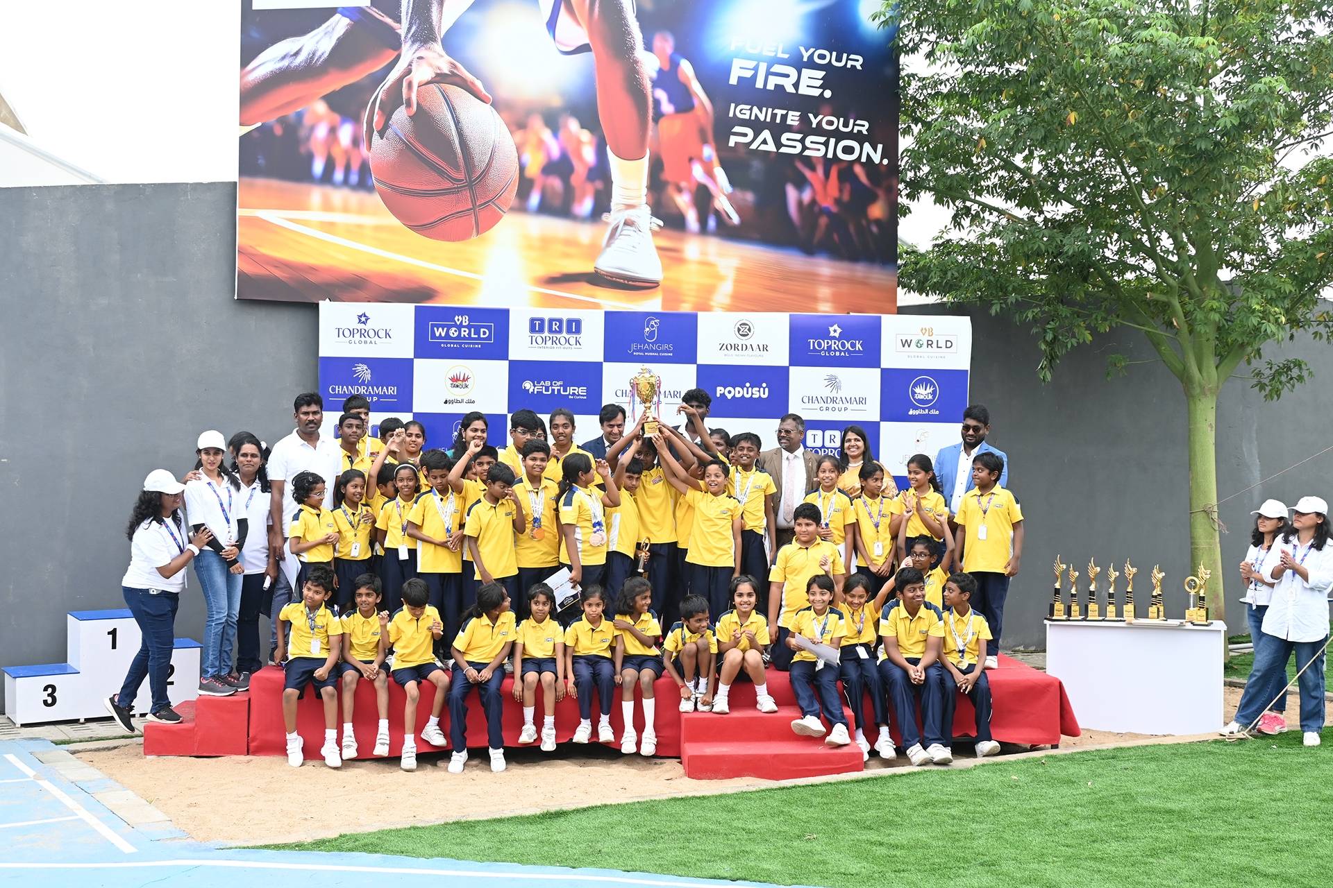 A group of CMIS school students proudly holding a winning trophy at their sports day.