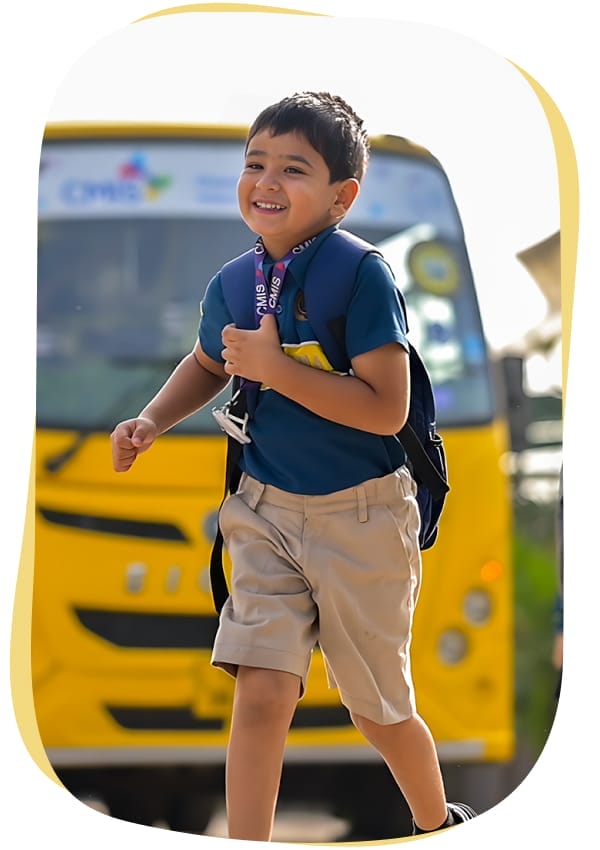 Smiling boy with backpack walking from yellow school bus.