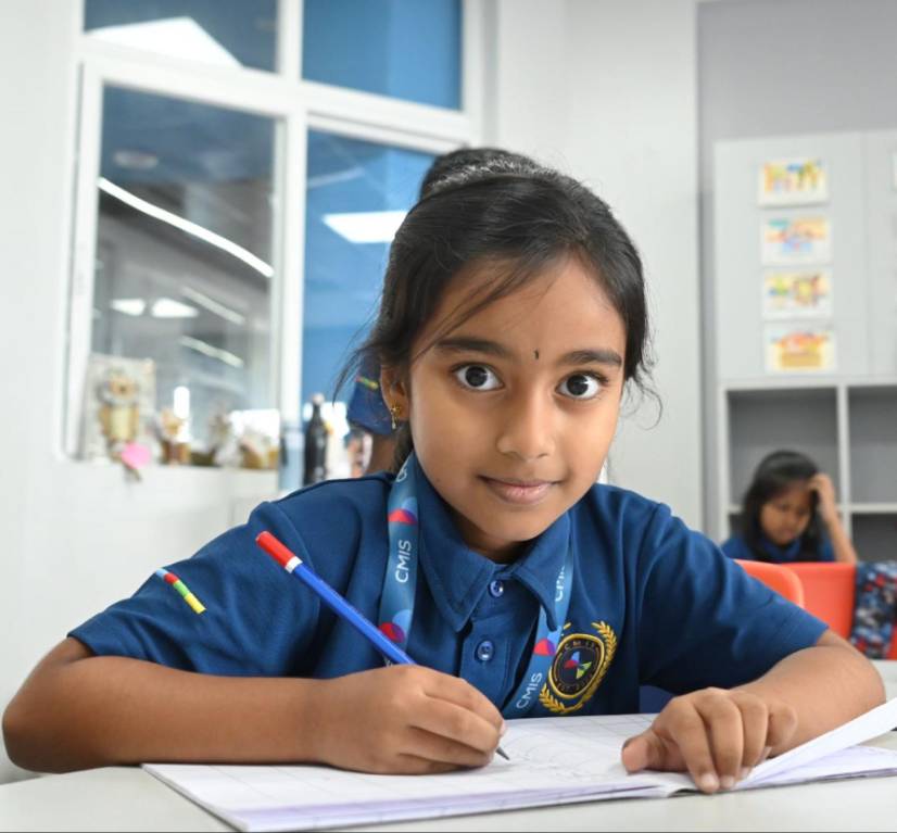 Teacher assisting students with classroom concepts at CMIS school.