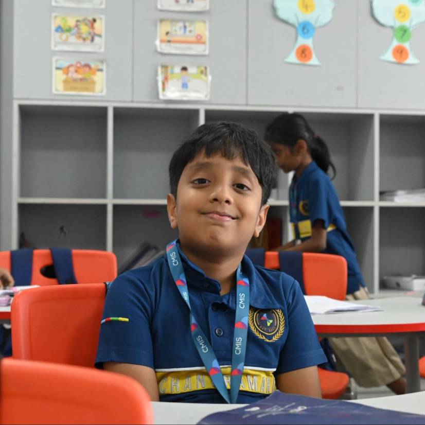 A smiling child in class shares a message of kindness, inspired by a neighbor’s struggle.